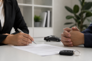 The image presents a realistic and minimalist representation of a financial agreement in a professional environment. Two individuals are positioned across a clean desk while a contract, a pen, and subtle automotive elements symbolize financial responsibility and shared accountability. The balanced lighting and neutral tones reinforce the serious and cautious atmosphere associated with credit obligations and financial commitment in the United States.
